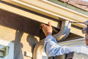 Worker Attaching Aluminum Rain Gutter and Down Spout