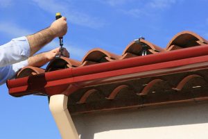 Man installing pvc rain gutter system on a house