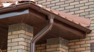 Corner of house with brown rain gutters and gutter guards.